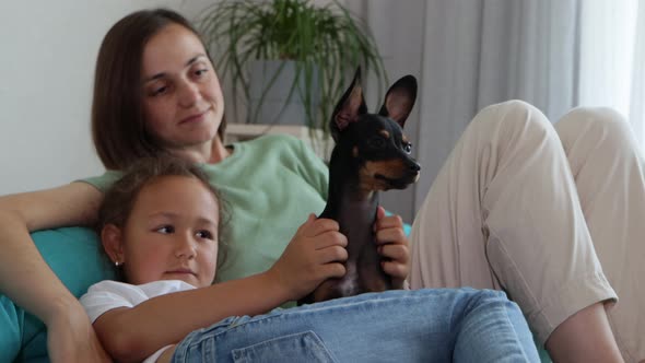 Mother and Daughter Having a Good Time with Dog at Sofa
