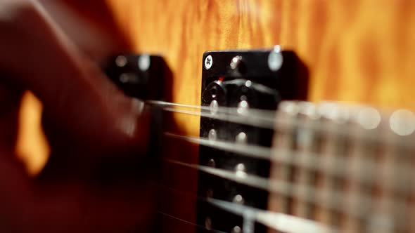 Male musician plays with pick on strings of an electric guitar, closeup hands. Musician plays electr alt