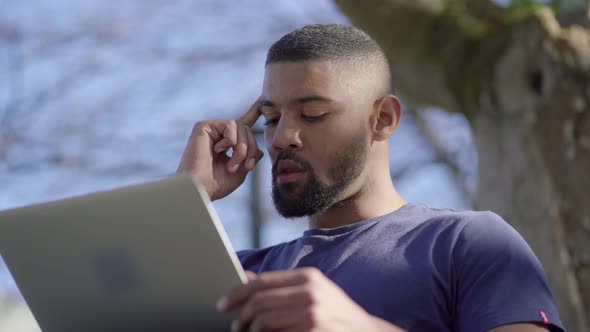 Afro-American Man Looking Around, Thinking, Typing on Laptop alt