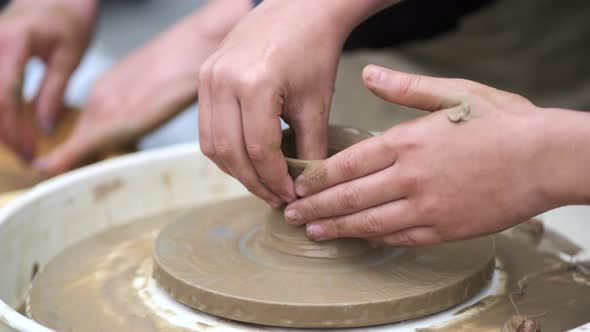Closeup of the Boy's Hands Sculpting Clay Dishes on a Potter's Wheel
