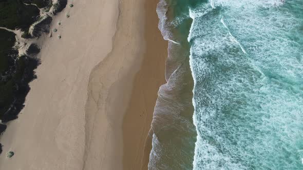 Aerial - Gentle waves running onto pristine beach, ascending top-down shot alt