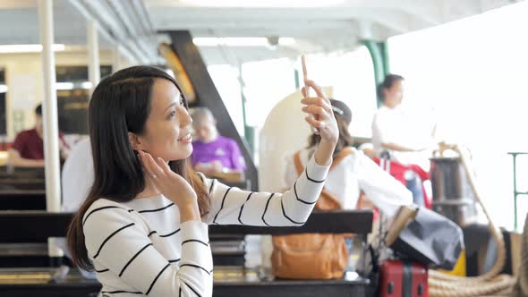 Woman taking photo with cellphone on star ferry in Hong Kong alt
