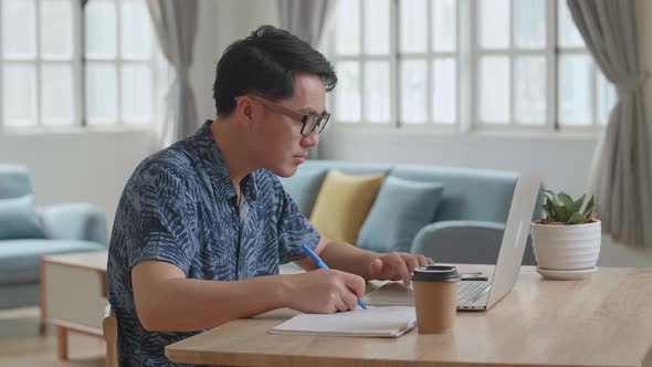 Man Using Laptop Computer And Writing On Notebook, Work From Home alt