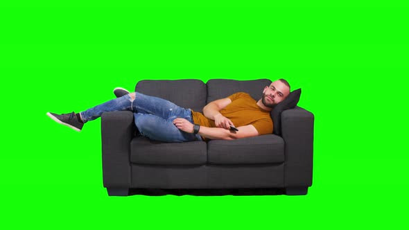 Man Lying Down on Sofa and Watching Tv Green Background