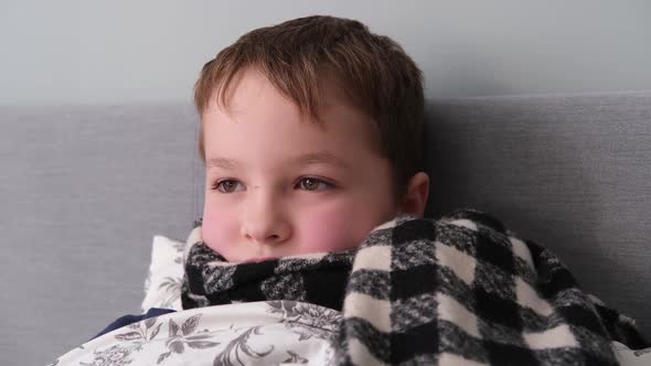 a Little Boy is Sick Lies in Bed in a Scarf