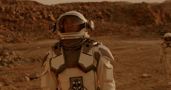 Male Astronaut Looking Around and Talking Near Colleague on Mars alt