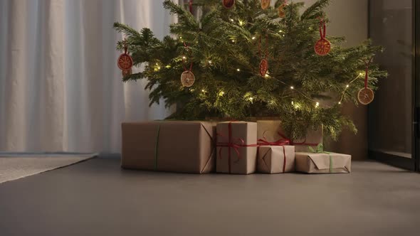 Handheld Ascent Shot of Christmas Tree with Present Boxes Indoor with Warm Light
