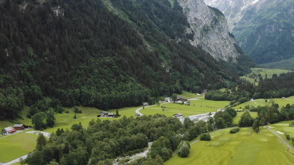 Beautiful Aerial Shot of Little Chalet Houses on the Foot of Mountain in Gorgeous Green Switzerland alt