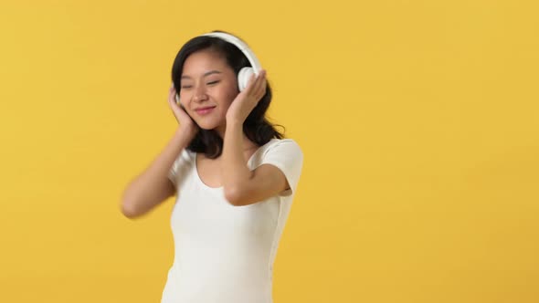 Young pretty Asian girl enjoyed listening to music from headphones smiling