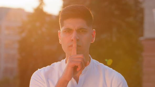Young Man Eastern Businessman Hold Finger on Lips Look at Camera Makes Hush Gesture Sharing Hidden alt
