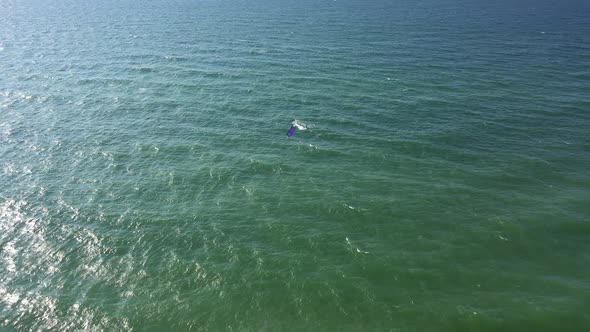 AERIAL: Wide Shot of Isolated Surfer with His Power Kite Surfing on a Windy Bright Day