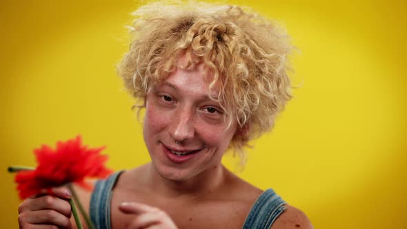 Closeup Portrait of Young Smiling Happy LGBT Man Putting Red Flower in Red Curly Hair Looking at alt