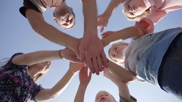 Friendly Family Join Hands Center Against Blue Sky alt