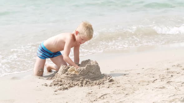 Little Blonde Boy Playing with Sand on Beach Ocean Sea
