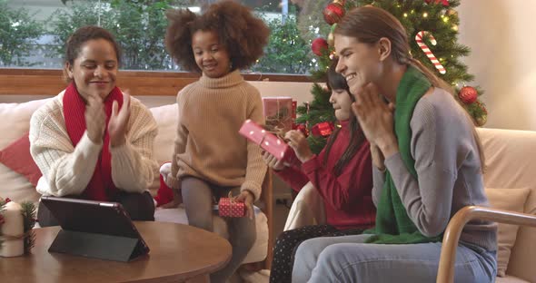 Mothers and kids celebrating Christmas at home and video calling to their families on tablet