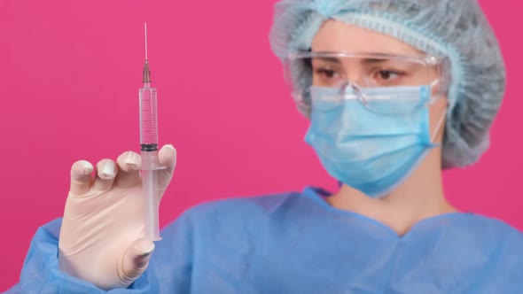 Professional Female Doctor Holds a Syringe with a Vaccine on a Pink Background alt