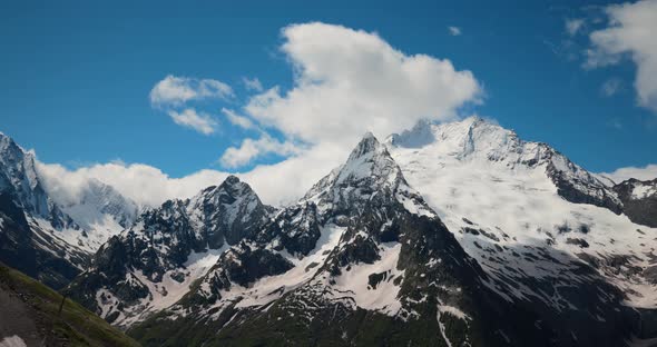 Air Flight Through Mountain Clouds Over Beautiful Snowcapped Peaks of Mountains and Glaciers alt