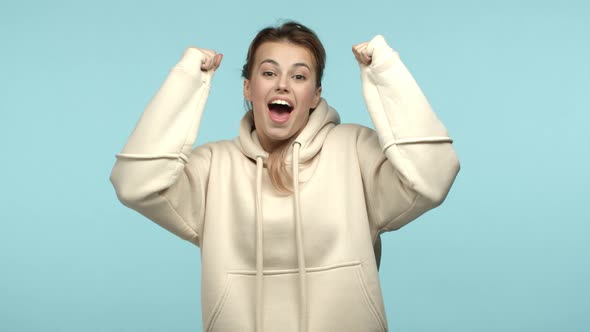 Slow Motion of Beautiful Blonde Girl in White Hoodie Celebrating Making Fist Pump and Rooting for alt