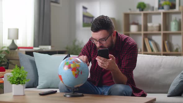 Young Handsome Guy Buying Tickets Via Mobile App While Sitting in His Living Room alt
