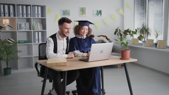 Happy Young Couple Man and Woman in Academic Mantle and Hat Rejoice at Diploma and Graduation alt