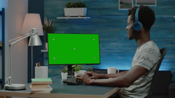 Man Looking at Horizontal Green Screen on Computer for Remote Work alt
