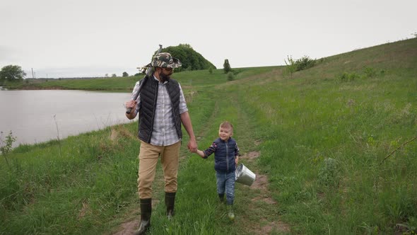 Dad and His Little Son Go Fishing Along the Lake
