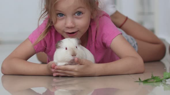 Blonde Cute Girl Without Milk Tooth Plays with a Domestic Rat on a Blurred Background at Home