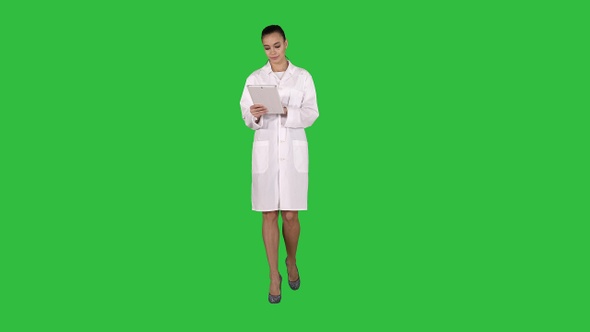 Doctor using tablet while walking on a Green Screen, Chroma Key alt