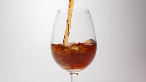 Brown beverage pour into a glass on a white background