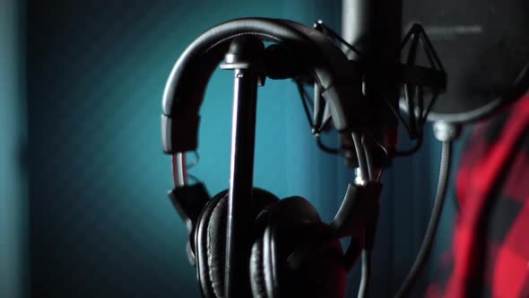 Closeup Hands of Singer Taking Off Headphones of Rack for Microphone at Music Record Studio alt