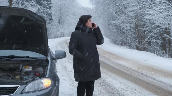 A Woman Calls on Her Smartphone While Standing By Broken Car