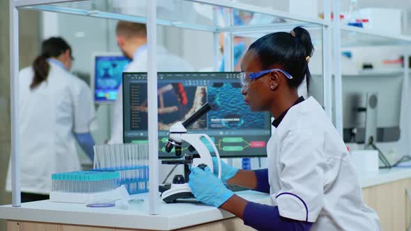 Black Biochemist Woman Sitting in Lab Analysing Blood Tests alt