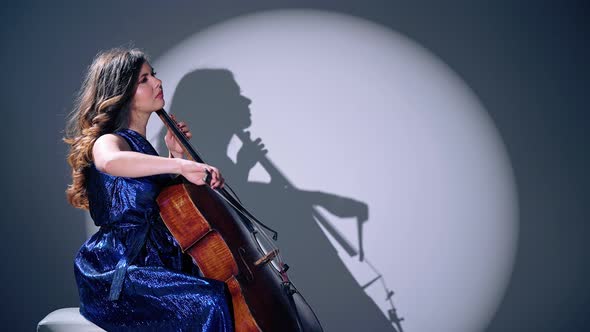 Young Beautiful Woman Playing on Cello in the Spotlight, Grey Background