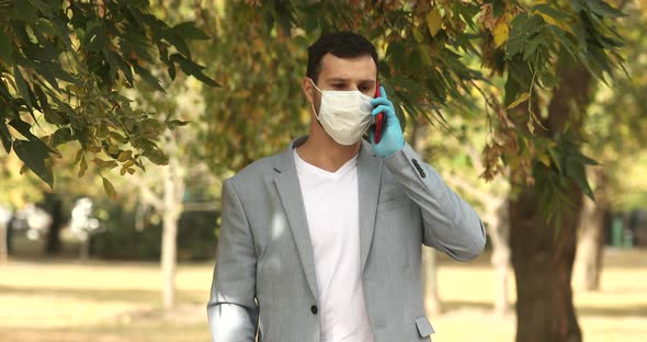 Closeup angry guy in face mask shouting on mobile phone outdoors. alt