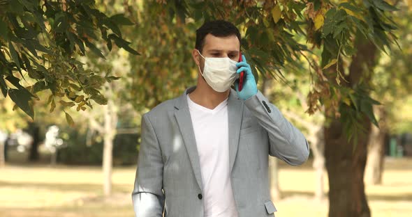 Closeup angry guy in face mask shouting on mobile phone outdoors.