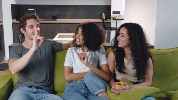 Group of Three Friends One Man and Two Women Talking Laughing Together While Sitting on the Couch alt