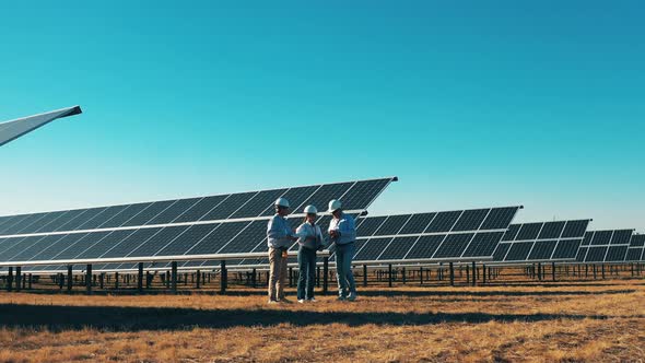 Safety Inspectors Are Walking Along the Photovoltaic Power Field. Engineers Working at Solar Energy alt