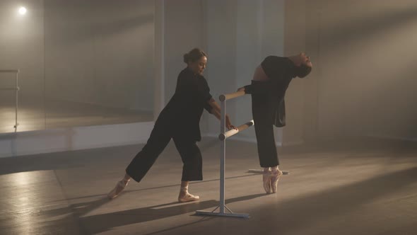 Wide Shot of Two Gorgeous Slim Flexible Women Dancing at Ballet Barre in Backlit Fog alt