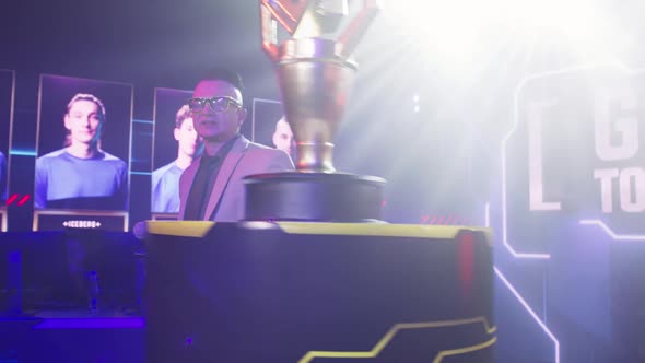 Male Announcer Showing Gaming Tournament Trophy alt