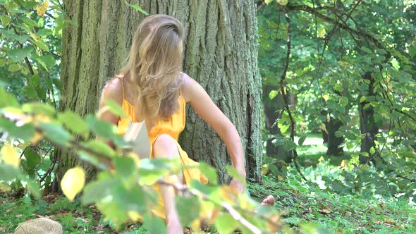 Young Woman Finished Reading Book under Thick Tree Trunk