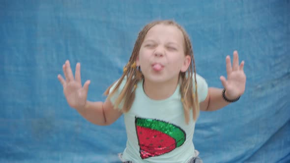 Young Girl with Pigtails Shows Her Tongue and Smiles Looking Into Camera alt