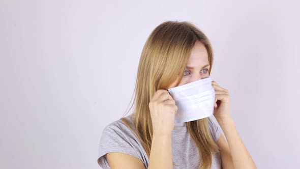 Young Woman Rubs Her Face and Puts on a Medical Mask