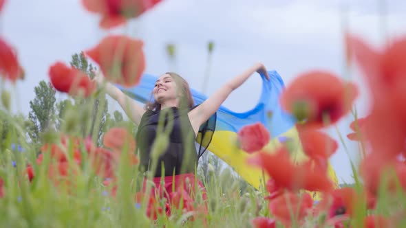 Portrait Cute Adorable Young Woman Dancing in a Poppy Field Holding Flag of Ukraine in Hands alt