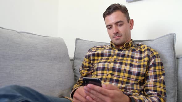 Young man using mobile phone in living room at home 4k