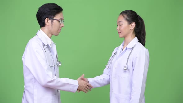 Young Asian Couple Doctors Shaking Hands Together