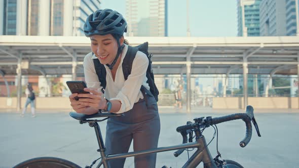 asian businesswoman with backpack use smart phone look camera in city stand at street with bike.