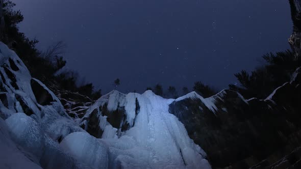 Time Lapse of Starry Sky Over the Frozen Waterfall in the Siberian Forest. Krasnoyarsk Nature