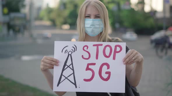 Blond Caucasian Woman in Face Mask Protesting Against 5G Mobile Towers. Rack Focus Changes From alt