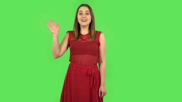 Tender Girl in Red Dress Is Waving Hand and Showing Gesture Come Here. Green Screen alt