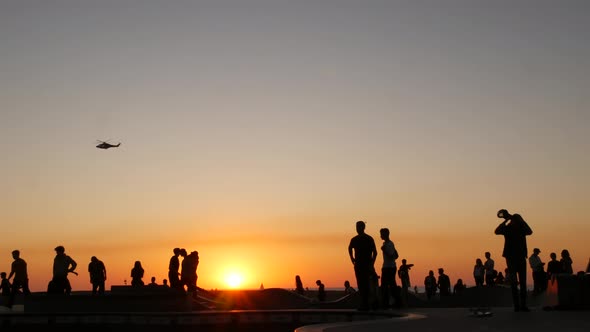 Silhouette of Young Jumping Skateboarder Riding Longboard, Summer Sunset Background. Venice Ocean alt